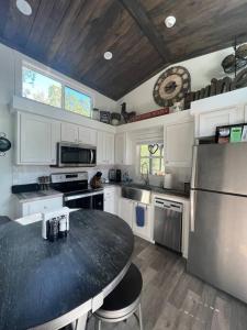 a kitchen with a black counter top and a refrigerator at Fox Hollow - Tiny home with Cypress Creek access, park like setting in Wimberley