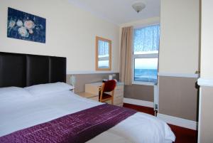 a hotel room with a bed and a desk and a window at At Caledonia in Douglas