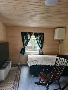 ein Schlafzimmer mit einem Bett, einem Stuhl und einem Fenster in der Unterkunft Mukavä mökki luonnon rauhassa maaseudulla. in Kokemäki