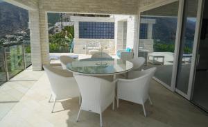 uma sala de jantar com uma mesa de vidro e cadeiras brancas em Villa Aleandra con Maravillosas Vistas al mar! em Altea
