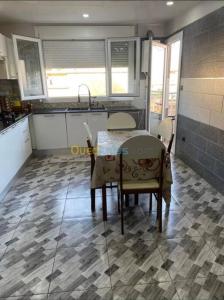 y cocina con mesa y sillas en el suelo de baldosa. en Appartement Ghazaouet, en Ghazaouet