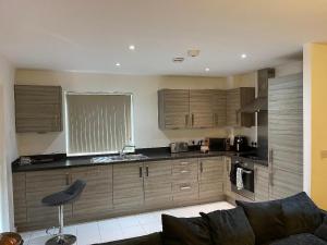 a kitchen with wooden cabinets and a couch in a room at Amazing Luxury Double Bedroom with en-suite shower and free parking with a Sound bar & smart TV in a two bed Apartment I live in the 2nd room in Belvedere