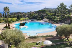 - une vue sur la grande piscine bordée d'arbres dans l'établissement St RAPHAEL - CAP ESTEREL Location Colette, à Saint-Raphaël