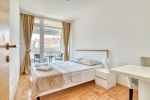 a white bedroom with a bed and a balcony at Sigma apartment in Budva