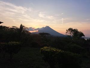 a mountain in the distance with the sun setting behind it at Hostel Santa Cruz Ometepe in Altagracia