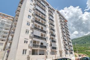 a tall apartment building with a mountain in the background at Sigma apartment in Budva