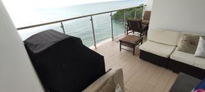 balcón con sofá y vistas al océano en Ph El Palmar Residenses, en El Nance