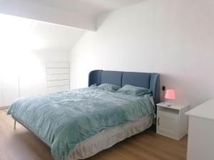 Schlafzimmer mit einem großen Bett mit blauem Kopfteil in der Unterkunft La Maison Heureuse in Châtelet