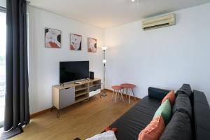 a living room with a couch and a flat screen tv at Atlantic West Town in Ponta Delgada