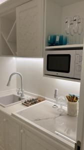 een witte keuken met een wastafel en een magnetron bij AMAREA Exclusive Suites in San Felice Circeo