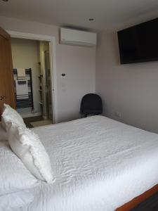 1 dormitorio con 1 cama blanca y TV en la pared en Self catering. Maydene. Holm. Orkney, Scotland. en Nether Button