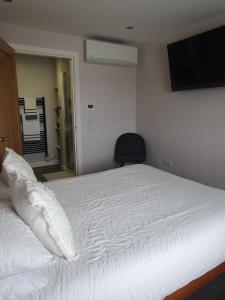 a bedroom with a white bed with a television on the wall at Self catering. Maydene. Holm. Orkney, Scotland. in Nether Button