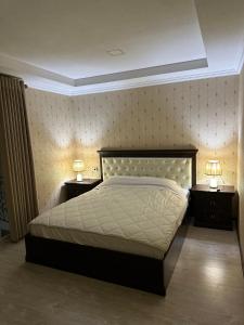 a bedroom with a large bed and two night stands with lamps at Hotel Latif Samarkand in Samarkand