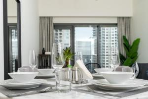 uma mesa de jantar com pratos brancos e copos em Ultimate Stay / 5 min walk from Dubai Mall / Brand New / Downtown em Dubai