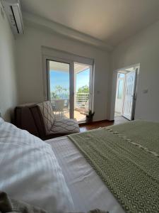 a bedroom with a bed and a chair and a balcony at Azzure Apartment in Ulcinj