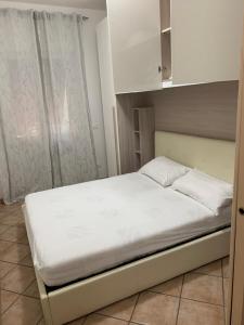 un letto in una piccola stanza con armadi bianchi di CASA AURORA a Porto Santo Stefano