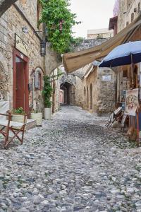 an alley in an old stone building with an umbrella at Old Town Luxury Velvet Apartment in Rhodes Town
