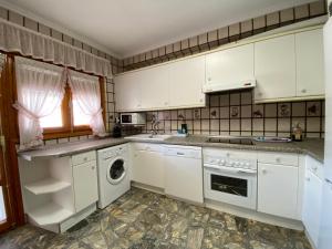 Una cocina con gabinetes blancos y lavadora y secadora. en Casa Juani, en Ateca
