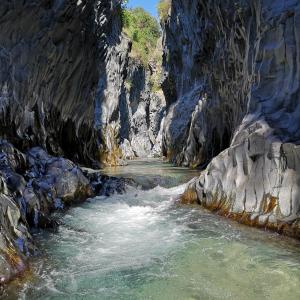 a painting of a river in a rocky canyon at Gole Alcantara mini Campeggio privato in Motta Camastra