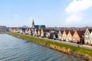 Luxury loft at lake Volendam 20 min. from Amsterdam CS في فولندام: صف منازل على شارع بجانب نهر