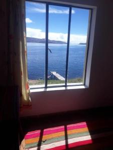 - une fenêtre dans une chambre avec vue sur l'océan dans l'établissement Hostal Luna del Titikaka en Isla de la Luna Bolivia, à Isla de la Luna