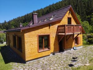 una pequeña casa de madera con terraza en un patio de piedra en Dom całoroczny JÓZEFINKA w Karkonoszach, en Kowary