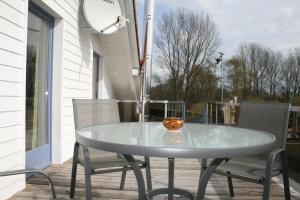 - une table en verre sur une terrasse couverte avec 2 chaises dans l'établissement FeWo, Ferienwohnung, Peenemünde im Naturschutzgebiet, à Peenemünde