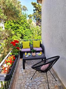 un patio con una mesa, un banco y flores en Apartment Ivy en Mlini
