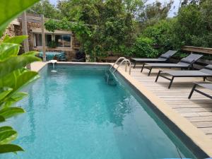 a swimming pool with chairs and a wooden deck at Salvacintoggio -Votre Villa avec Piscine Privée- in Porto-Vecchio