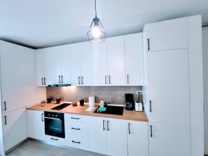 eine weiße Küche mit weißen Schränken und einer Leuchte in der Unterkunft ATENEO - Studio DeLuxe Modern Apartment, Big Balcony, Plus Parking in Timişoara