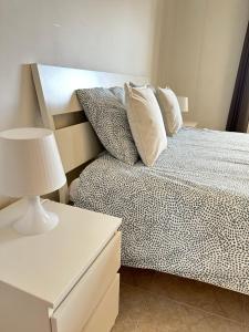 a bedroom with a bed with a lamp and a table at Alojamento Ramos in Quarteira