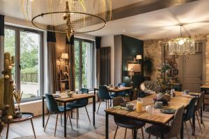 a restaurant with wooden tables and chairs and a chandelier at La Bastide de Barbizon in Barbizon