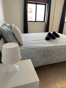 a bedroom with a bed with two blue slippers on it at Alojamento Ramos in Quarteira