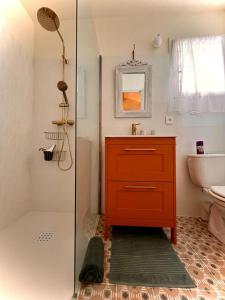 ein Badezimmer mit einem roten Schrank und einer Glasdusche in der Unterkunft Charmant logement provençal avec piscine à deux pas du village médieval in Seillans