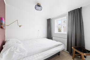 a white bedroom with a bed and a window at Downtown Baldursbrá Holiday Home in Reykjavík