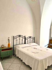 a bedroom with a bed with a white blanket and a table at Dimora Galerana, Oria città del Salento in Oria