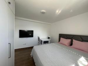 a bedroom with a bed with pink pillows and a desk at Azzure Apartment in Ulcinj