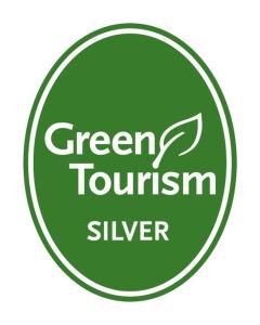 a green tourism silver sign in a green circle at Hound and Human Holiday Cottage - Redgrave, Suffolk in Diss