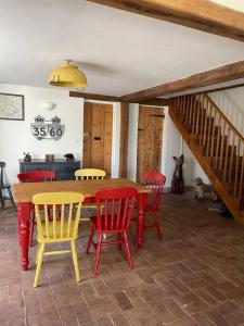 een eetkamer met een tafel en rode en gele stoelen bij Hound and Human Holiday Cottage - Redgrave, Suffolk in Diss