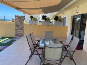 a glass table and chairs on a patio at Duplex con piscina individual y vistas al mar en Torrevieja in Torrevieja