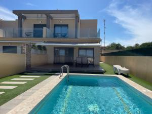 a villa with a swimming pool in front of a house at Duplex con piscina individual y vistas al mar en Torrevieja in Torrevieja