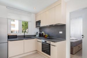 a kitchen with white cabinets and a black counter top at La Suite Apartments 2 in Promajna