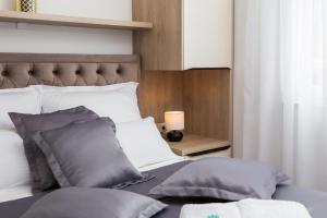 ein Bett mit grauen Kissen und einer Lampe auf dem Tisch in der Unterkunft La Suite Apartments 2 in Promajna