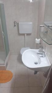 La salle de bains est pourvue d'un lavabo blanc et de toilettes. dans l'établissement Apartment Bepo, à Seget Vranjica