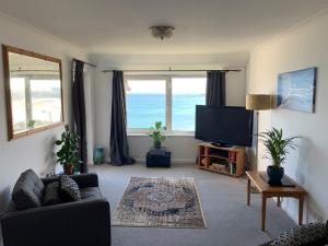 a living room with a couch and a flat screen tv at Two bed flat with stunning views over Fistral Bay! in Newquay