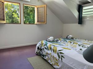 una camera con un letto e due finestre di La Belle Epoque (3*) - Maison avec vue sur mer à Bouillante a Bouillante