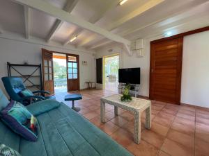 sala de estar con sofá azul y mesa en La Belle Epoque (3*) - Maison avec vue sur mer à Bouillante, en Bouillante