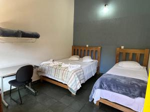 a room with two beds and a desk and a desk at Hotel dos Sonhos in São Thomé das Letras