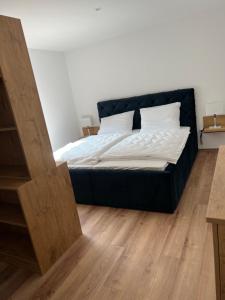 uma cama com lençóis brancos e almofadas num quarto em Seeblick Apartment am Mellensee em Mellensee