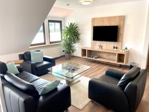 a living room with two couches and a flat screen tv at Hotel garni "Café im Hamm" in Zell an der Mosel